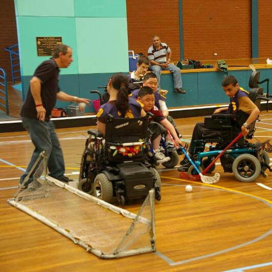 Group of young athletes playing wheelchair lacrosse at an inclusive camp for kids and youth with disabilities.